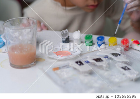 Cute little girl making DIY plaster and painting at home. Close-up of children painting on plaster sculpture with family on holiday. Imagination and creativity activities. 105686598