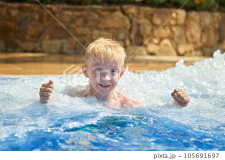 Young boy kid child eight years old splashing in swimming pool having fun leisure activity. Boy happy swimming in a pool. Activities on the pool, children swimming and playing in water, happiness and 105691697