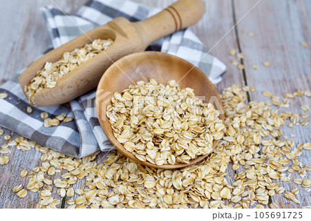 Oatmeal or oat flakes in bowl and scoop on rustic table. Concept of healthy eating 105691725