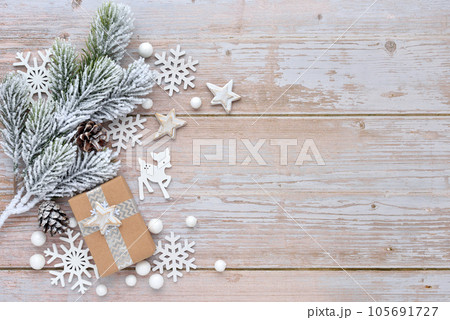 Spruce branch in the snow with Christmas decorations on the background of a light wooden table. 105691727