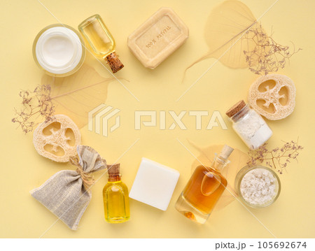 Organic cosmetic - bath salt, cream, bottles of essential oils, soap on a yellow pastel background. Organic cosmetic - bath salt, cream, bottles of essential oils, soap on a yellow pastel background. 105692674