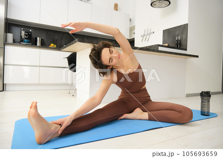 Image of brunette girl, stretching her legs, doing fitness workout, feet exercises to warm up before yoga, training at home alone 105693659