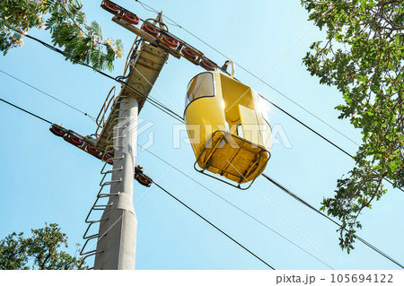 Yellow cabin of overhead cable car against blue sky Yellow cabin of overhead cable car against blue sky 105694122