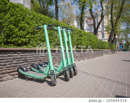 【ウクライナ】首都キーウの石畳の歩道に駐車された4台の黄緑色の電動スクーター 105695314