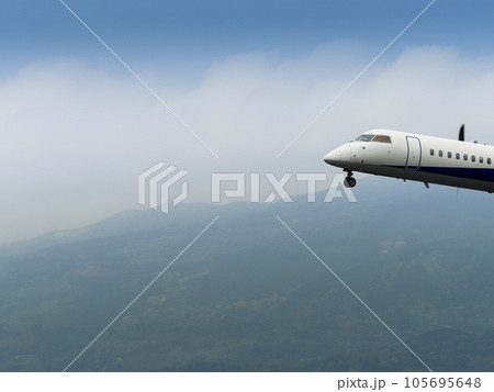 山間の空を飛行する旅客機 105695648