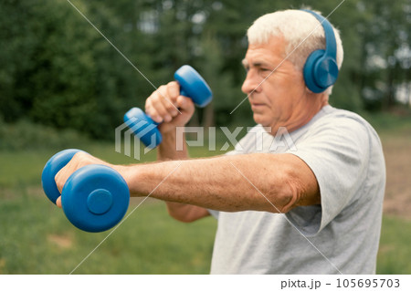 Senior man working out outdoors. Person lifting dumbbells. Old male exercising at park. Healthy people lifestyle. Active sport training. Older elderly sportsman doing fitness exercise. Workout session 105695703