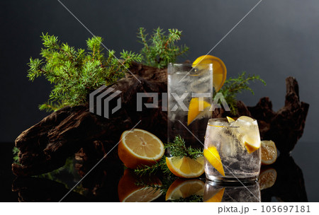 Cocktail gin-tonic with ice and lemon on a black reflective background. 105697181