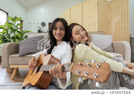 LGBTQIA lesbian gay couple playing guitar and singing with romantic feelings at home 105697688