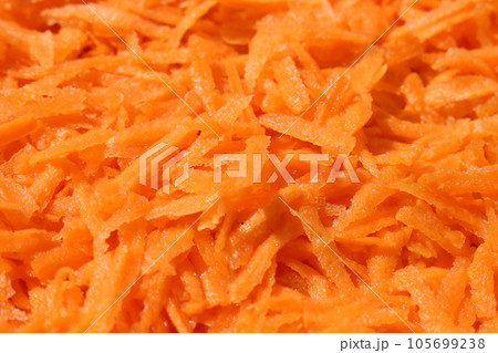 Carrots, grated on a large grater. Food orange background. Carrots, grated on a large grater. Food orange background. 105699238
