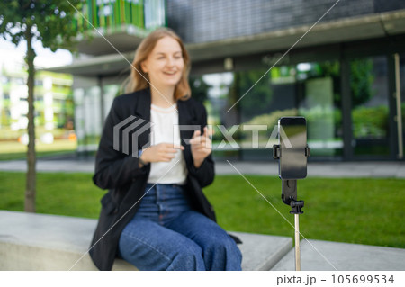 Female teen vlogger recording video using smartphone on tripod 105699534