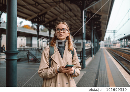 Angry lost woman waiting on the station platform and using smart phone at the airport link station, Gdansk, Poland. 105699559