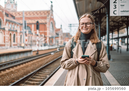 Young unhappy lost woman crying and waiting train on station platform. She using smart phone. Young unhappy lost woman crying and waiting train on station platform. She using smart phone. 105699560
