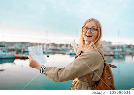 Happy traveler woman with a map and backpack on a lake pier, feeling freedom and enjoying. Travel around Europe. High quality photo Happy traveler woman with a map and backpack on a lake pier, feeling freedom and enjoying. Travel around Europe. High quality photo 105699631