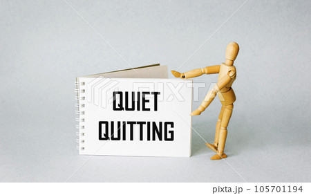 Quiet quitting symbol. Silent care concept words on notepad. Light background. Wooden puppet . Quiet quitting symbol. Silent care concept words on notepad. Light background. Wooden puppet . 105701194