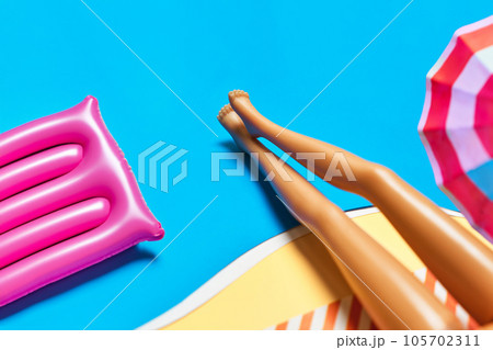Inflatable pool toy flamingo with doll legs on a blue background. 105702311