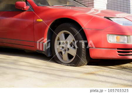 パンクしたまま放置された赤いスポーツカー 105703325