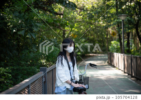 Asian woman riding a bicycle in the park. 105704128