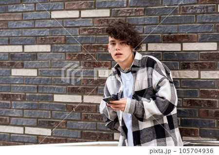 young man with a phone against a brick wall 105704936