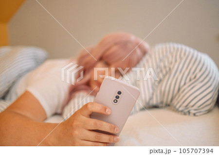 Shocked young woman laying in bed and looking at alarm at smartphone in bedroom at home. Shocked young woman laying in bed and looking at alarm at smartphone in bedroom at home. 105707394