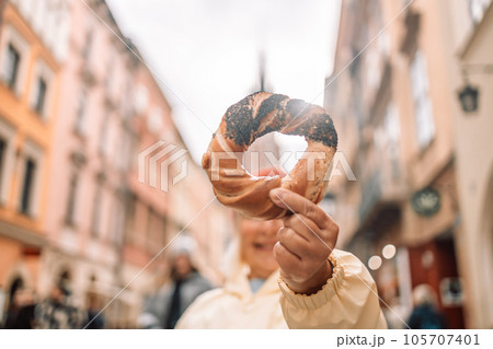Senior woman holding prezel, traditional polish snack on the Market square in Krakow Senior woman holding prezel, traditional polish snack on the Market square in Krakow 105707401