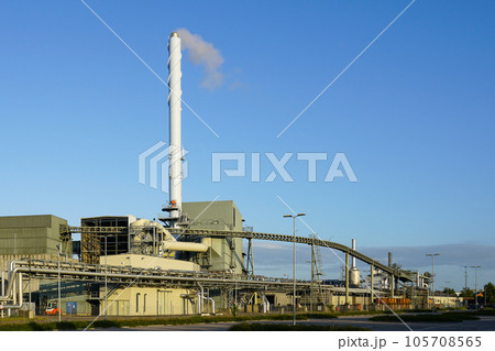 External view of large modern biomass cogeneration wood chip power plant with tall steam chimney External view of large modern biomass cogeneration wood chip power plant with tall steam chimney 105708565