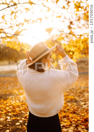 Sunny lifestyle portrait of young stylish woman walking on park, wearing cute trendy hat. Fashion concept. 105709056