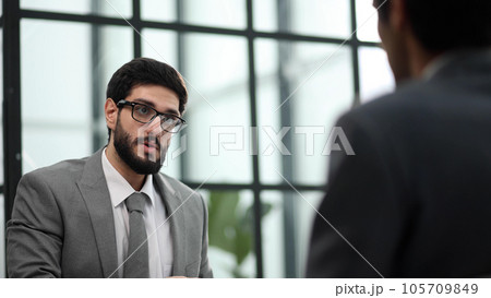 the manager receives a partner in his office sitting at the table 105709849