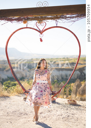 Girl sitting on a decorated heart-shaped bench on a viewpoint and admiring view of Cappadocia 105709954
