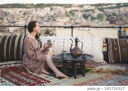 beautiful girl is relaxing with a cup of tea on the sofa in Turkish style and interior beautiful girl is relaxing with a cup of tea on the sofa in Turkish style and interior 105710327