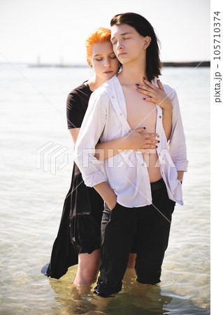 two lovers boy and girl are happy walking and hugging on the sandy beach near the sea. two lovers boy and girl are happy walking and hugging on the sandy beach near the sea. 105710374
