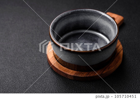 Empty round ceramic bowl on a wooden cutting board in brown color 105710451