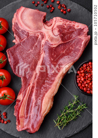 Raw fresh juicy beef t-bone steak with salt, spices and herbs 105710502