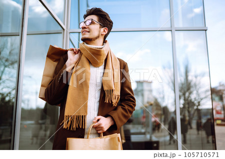 Stylish man with paper packages after shopping. Sale, consumerist, lifestyle concept. 105710571