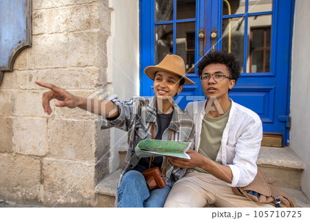 Young couple sitting on the door step and discussing the route Young couple sitting on the door step and discussing the route 105710725