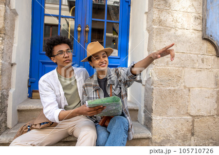 Young couple sitting on the door step and discussing the route Young couple sitting on the door step and discussing the route 105710726