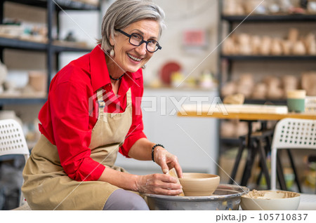 Woman making clay plate on a potter's wheel in the handcraft workshop. 105710837