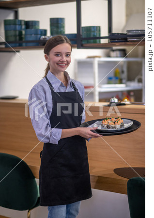 Female waitress carrying a plate with sushi 105711107