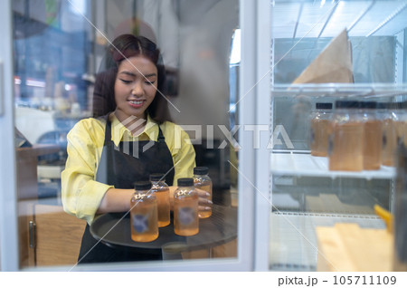 Young girl in apron taking drinks from the fridge 105711109