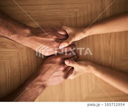Man and woman holding hands on a table and supporting, helping and comfort each other in marriage couple counseling session from above view. Loving husband and wife touching each other showing care 105712054