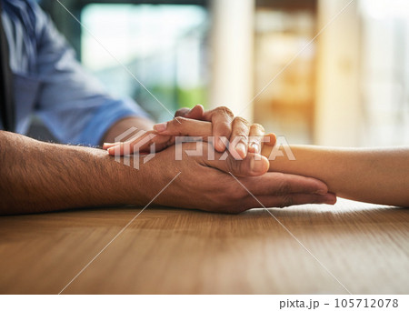 Hands holding together with love, support and care in a touching and bonding moment. Closeup of a close, loving hand hold between two people together. Comforting gesture of sympathy and community 105712078