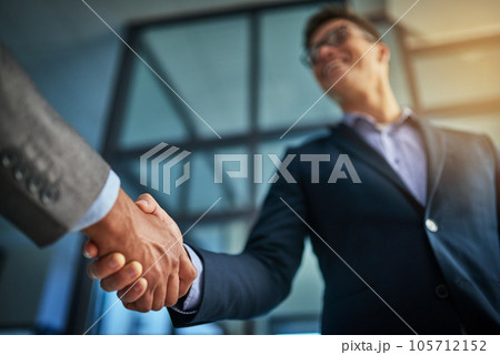 A professional handshake after a successful group collaboration meeting after in a modern corporate office. Young man shaking customers hands after sealing a business contract deal for the company A professional handshake after a successful group collaboration meeting after in a modern corporate office. Young man shaking customers hands after sealing a business contract deal for the company 105712152