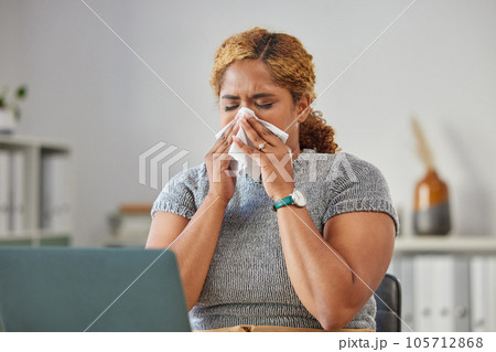 Sick, ill, or unwell business woman suffering with a cold, flu or sinus infection and sneezing or blowing her nose with a tissue. Young female remote working on her laptop from the home office Sick, ill, or unwell business woman suffering with a cold, flu or sinus infection and sneezing or blowing her nose with a tissue. Young female remote working on her laptop from the home office 105712868