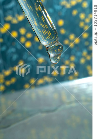 A dripping pipette with a drop of cosmetics gel. 105714918