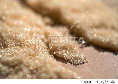 The texture of a yellow shining scrub on a beige background. The texture of a yellow shining scrub on a beige background. 105715108