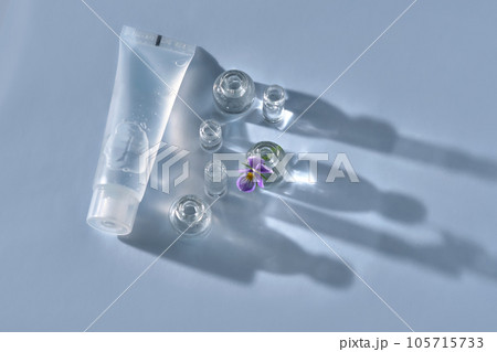 Transparent bottle of cosmetic gel on a blue background with small bottles of water. Transparent bottle of cosmetic gel on a blue background with small bottles of water. 105715733