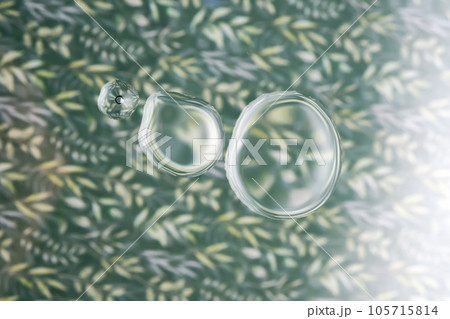 Three drops of cosmetic transparent gel on a green background. The texture of the serum. 105715814