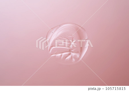 Drop of cosmetic transparent gel on a pink background. The texture of the serum, heir gel or hyaluronic booster. 105715815