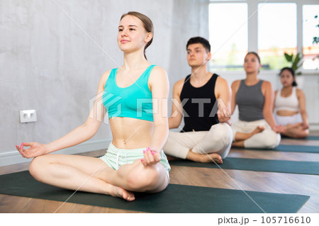 Young lady performs comfortable half-lotus pose, Ardha padmasana 105716610