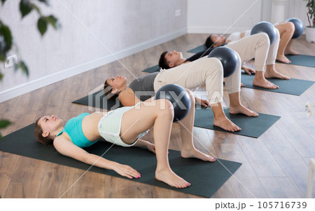 Young girl practicing pilates pose with softball between legs in training area 105716739