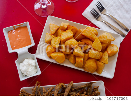 Spicy potatoes Patatas bravas with sauces and fried anchovies 105717008